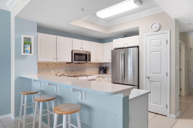 kitchen featuring white cabinets, decorative backsplash, crown molding, appliances with stainless steel finishes, and light tile patterned floors