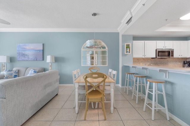 tiled dining space featuring a textured ceiling and ornamental molding