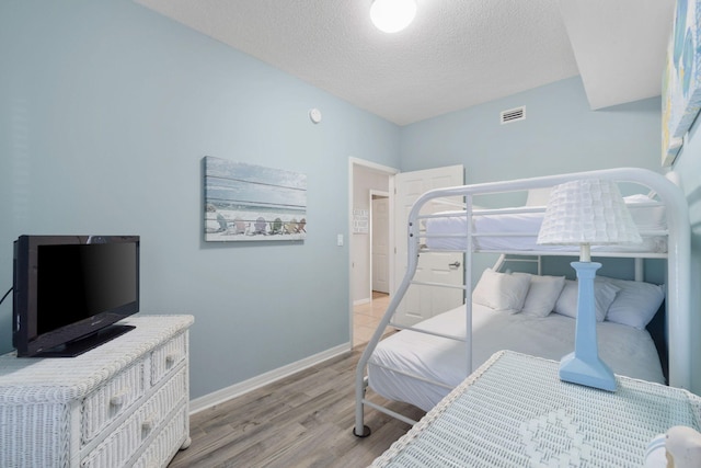 bedroom with a textured ceiling and light hardwood / wood-style flooring