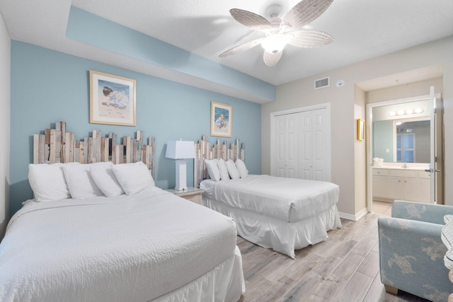 bedroom featuring ensuite bathroom, light hardwood / wood-style flooring, a closet, and ceiling fan