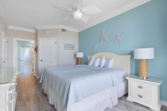 8573 Gulf Blvd Unit 703, Navarre, FL 32566 - bedroom featuring light wood-style flooring, crown molding, a textured ceiling, ceiling fan, and baseboards