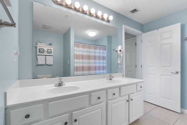 bathroom featuring double vanity, tile patterned flooring, toilet, and a textured ceiling