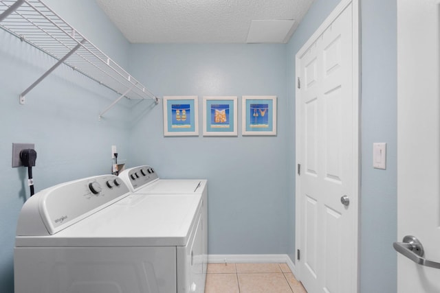 washroom featuring light tile patterned flooring, washing machine and dryer, and a textured ceiling