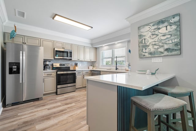 kitchen with ornamental molding, appliances with stainless steel finishes, kitchen peninsula, and a breakfast bar area