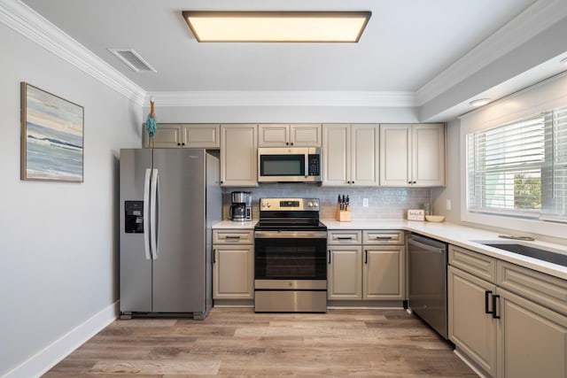 kitchen with crown molding, stainless steel appliances, tasteful backsplash, and light wood-type flooring