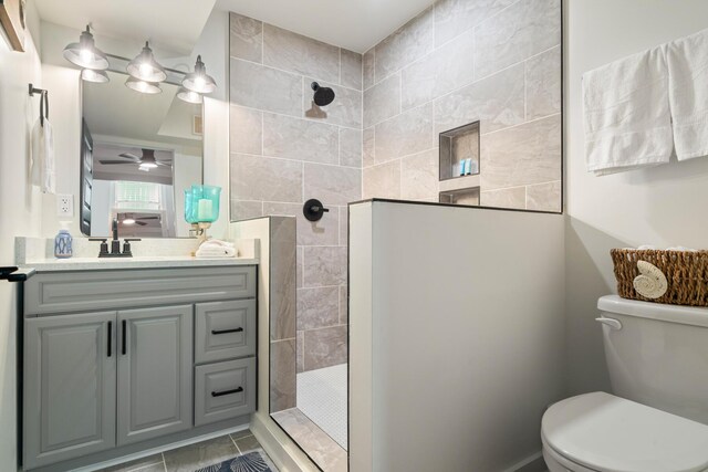 bathroom featuring vanity, tiled shower, and toilet