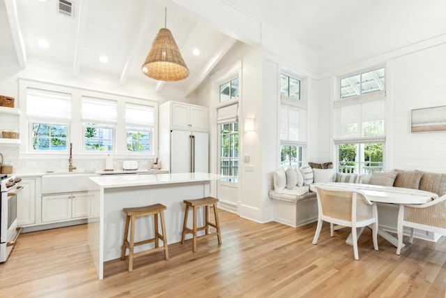 kitchen featuring sink, white cabinetry, high end refrigerator, hanging light fixtures, and breakfast area