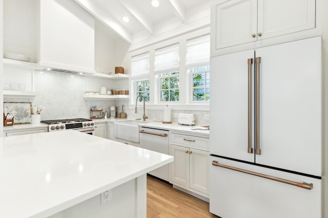 kitchen with beam ceiling, white cabinetry, sink, backsplash, and white appliances