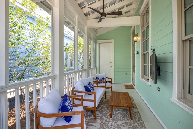 sunroom featuring lofted ceiling with beams, ceiling fan, and a wealth of natural light