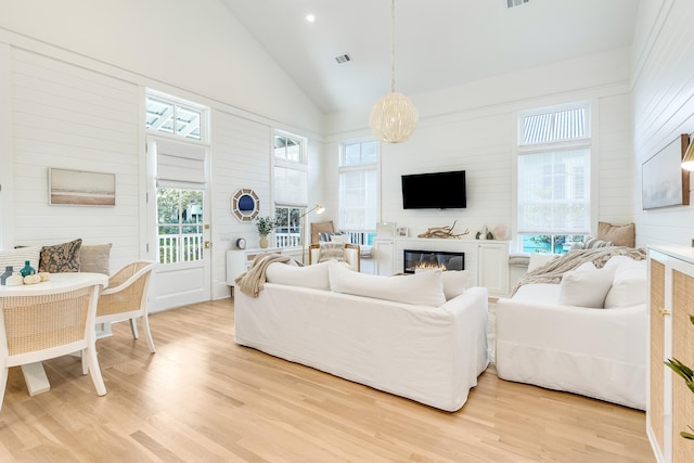 133 Silver Laurel Way, Santa Rosa Beach, FL 32459 - living area with light wood-style flooring, plenty of natural light, high vaulted ceiling, a glass covered fireplace, and wooden walls