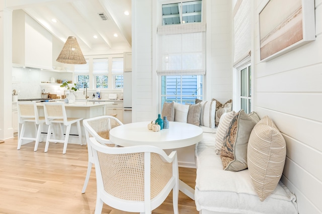 dining room with lofted ceiling with beams and light hardwood / wood-style floors