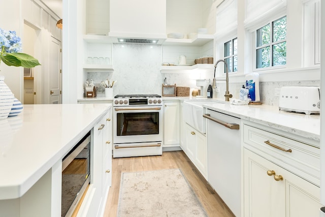 kitchen with tasteful backsplash, light hardwood / wood-style flooring, stainless steel microwave, white dishwasher, and gas range oven