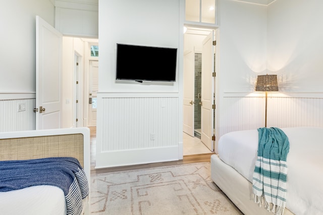 133 Silver Laurel Way, Santa Rosa Beach, FL 32459 - bedroom featuring a decorative wall, wainscoting, wood finished floors, and ensuite bathroom