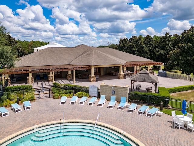 view of swimming pool with a hot tub, fence, a gazebo, and a patio area