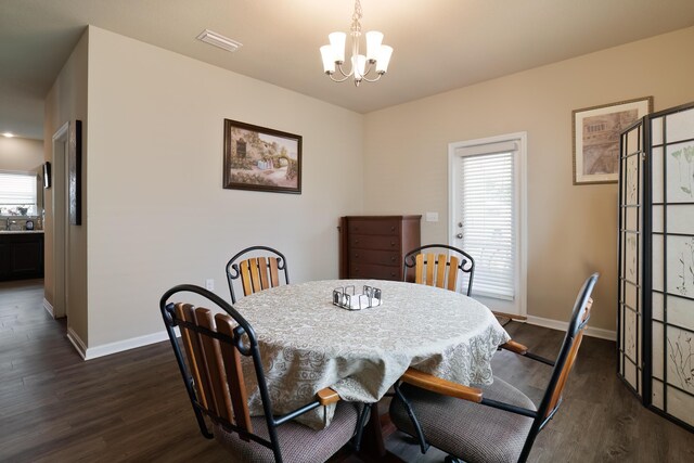 dining area with dark wood-type flooring and a chandelier