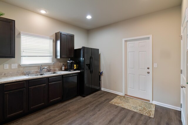 kitchen with sink, dark brown cabinetry, dark hardwood / wood-style flooring, and black appliances