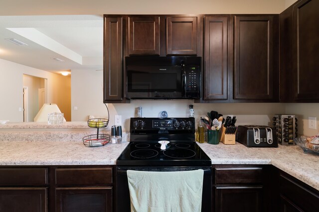 kitchen with a raised ceiling, dark brown cabinets, and black appliances