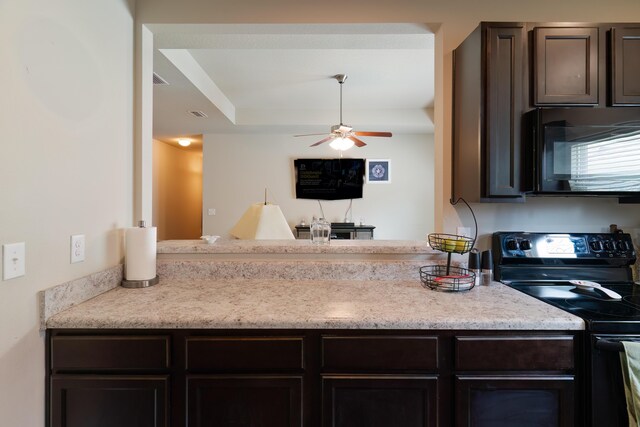 kitchen with ceiling fan, a raised ceiling, black appliances, and dark brown cabinets