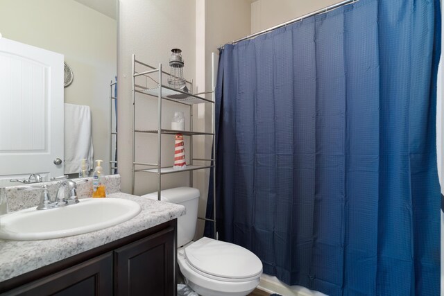 bathroom featuring toilet, vanity, and a shower with curtain