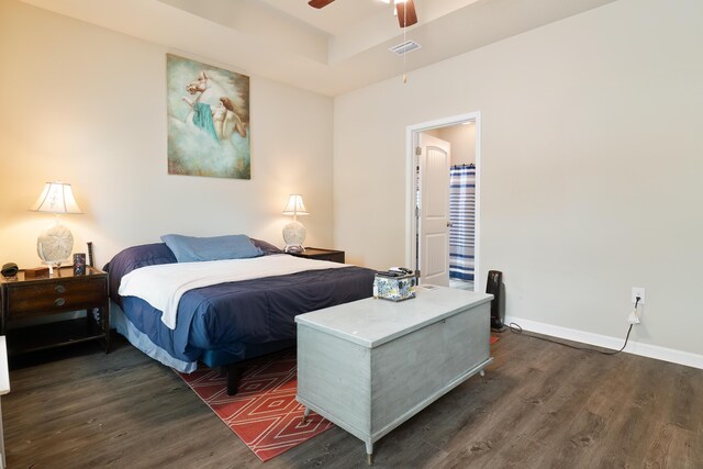 bedroom featuring dark hardwood / wood-style flooring, a tray ceiling, and ceiling fan