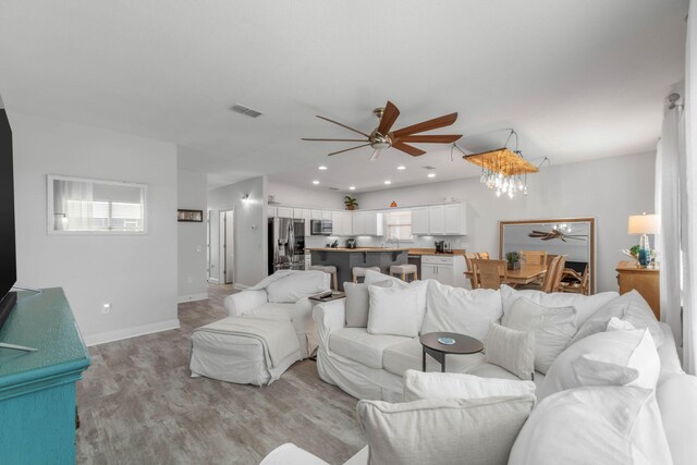 living room featuring a wealth of natural light, ceiling fan, and light wood-type flooring