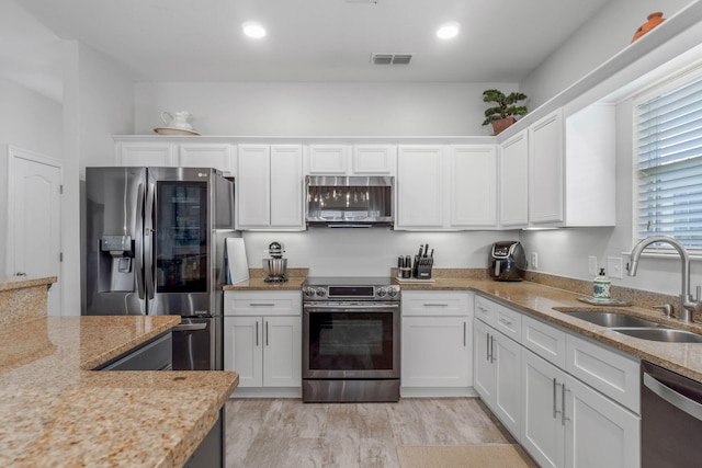 kitchen featuring light hardwood / wood-style flooring, white cabinetry, light stone counters, sink, and stainless steel appliances