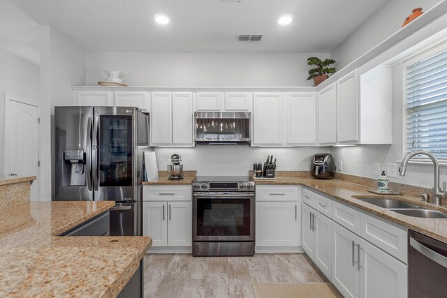 kitchen featuring appliances with stainless steel finishes, light stone countertops, sink, and white cabinets