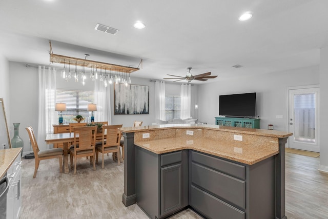 kitchen with light wood-type flooring, ceiling fan, light stone countertops, and gray cabinetry