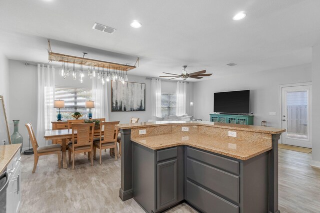 kitchen featuring light stone countertops, gray cabinets, and a kitchen island