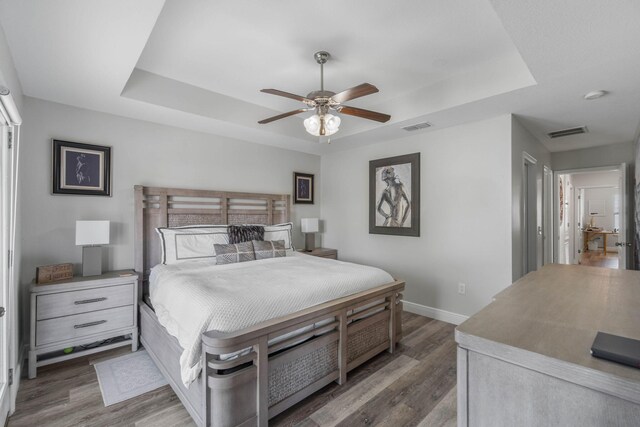 bedroom featuring ceiling fan, a raised ceiling, and dark hardwood / wood-style floors