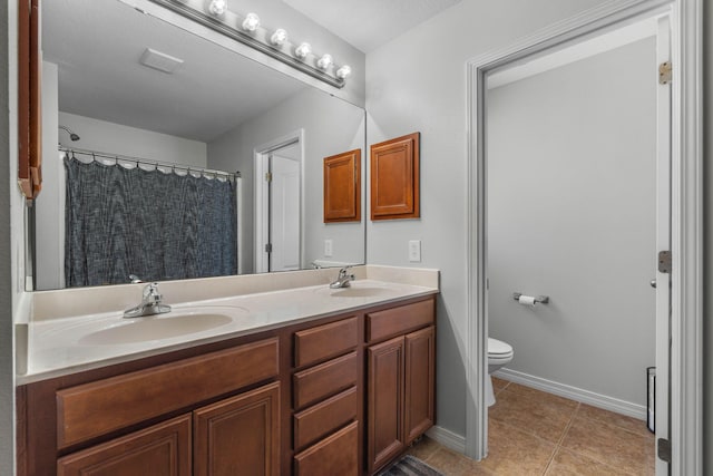 bathroom with tile patterned floors, toilet, and dual bowl vanity