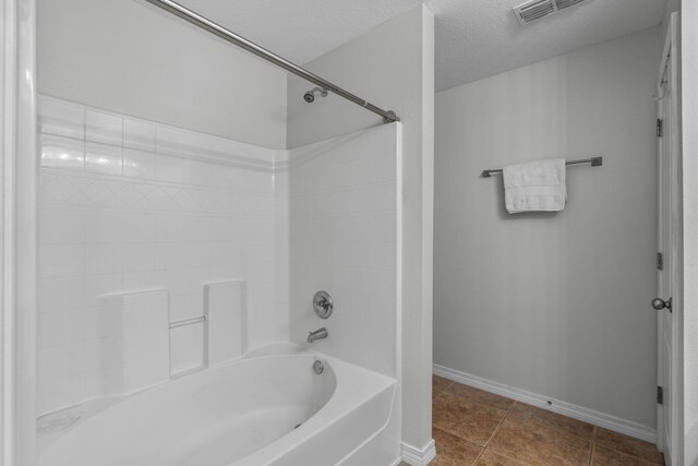 bathroom with tile patterned flooring, a textured ceiling, and  shower combination