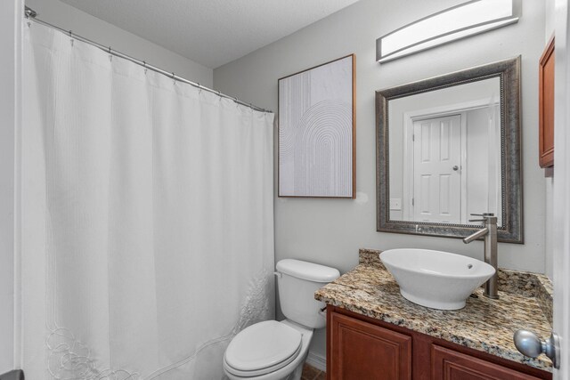 bathroom featuring vanity, a textured ceiling, and toilet