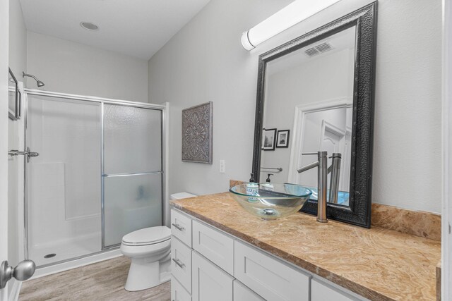 bathroom with a shower with door, toilet, vanity, and hardwood / wood-style flooring