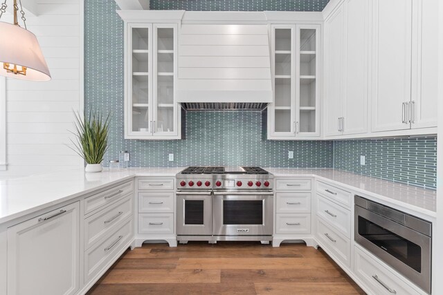 kitchen featuring hardwood / wood-style floors, decorative backsplash, appliances with stainless steel finishes, and white cabinets