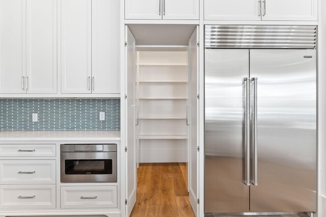 kitchen featuring light hardwood / wood-style flooring, white cabinetry, backsplash, and stainless steel appliances