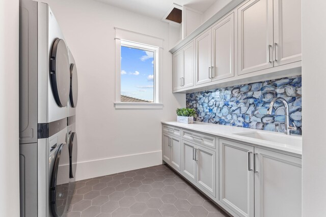 laundry room featuring tile patterned flooring, cabinets, sink, and stacked washing maching and dryer