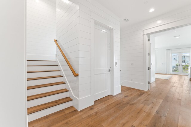 staircase with light hardwood / wood-style flooring and french doors