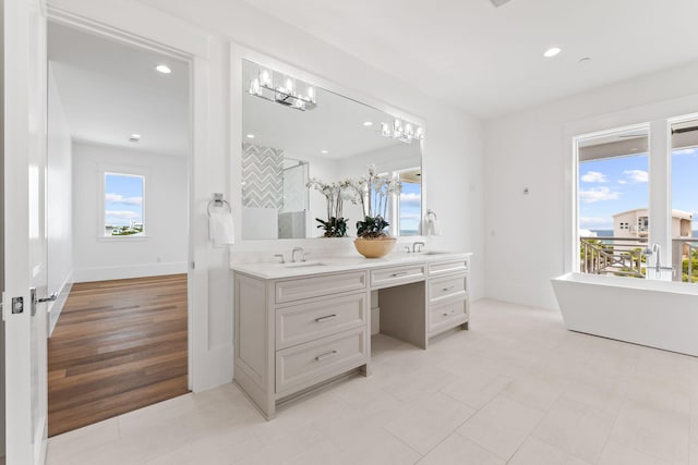 bathroom featuring vanity, tile patterned flooring, a bathing tub, and a healthy amount of sunlight