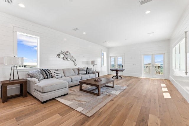 living room with light hardwood / wood-style flooring, a wealth of natural light, and french doors