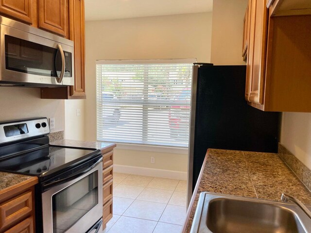 kitchen with stainless steel appliances, light tile patterned floors, and sink