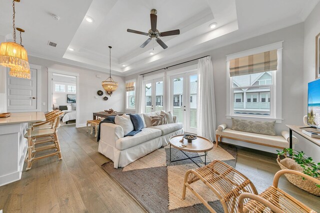 living room featuring light wood-type flooring, a tray ceiling, and ceiling fan