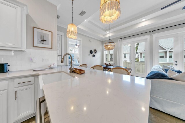 kitchen featuring hanging light fixtures, light stone countertops, ceiling fan with notable chandelier, decorative backsplash, and white cabinets