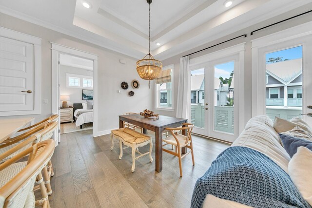 dining space with a raised ceiling, a chandelier, and light hardwood / wood-style floors