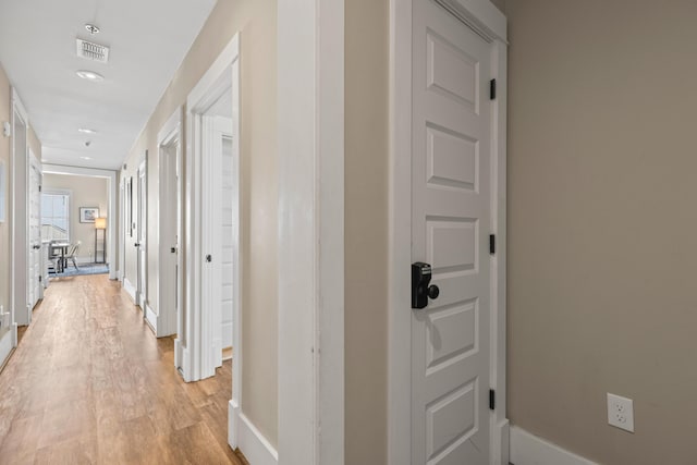 corridor with baseboards, visible vents, and light wood-style floors