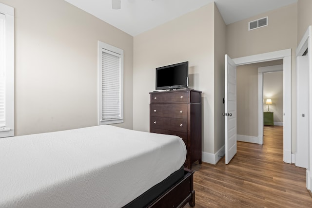 bedroom featuring baseboards, visible vents, a ceiling fan, and wood finished floors