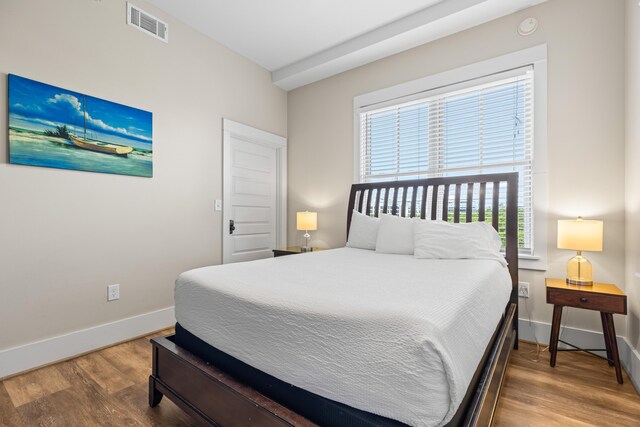 bedroom with baseboards, visible vents, and wood finished floors
