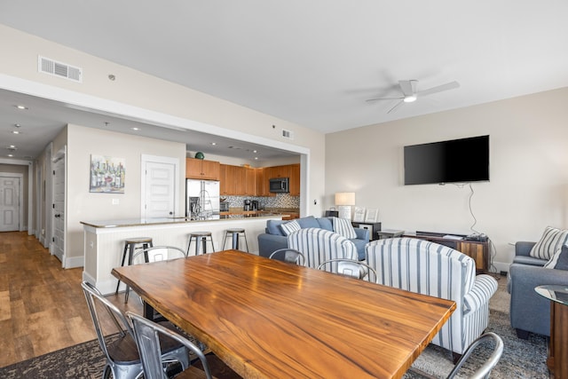 dining room featuring wood finished floors, visible vents, baseboards, and ceiling fan