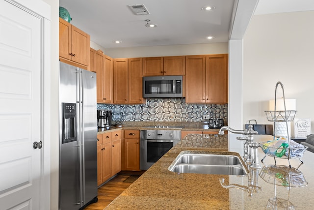 kitchen with stone counters, stainless steel appliances, dark wood-type flooring, tasteful backsplash, and sink