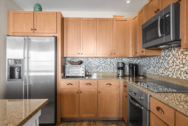 kitchen with dark wood-type flooring, a toaster, decorative backsplash, light stone counters, and appliances with stainless steel finishes